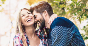 30-something couple laughing together with big, complete smiles