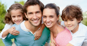 Family of four smiles, showing off their beautiful teeth